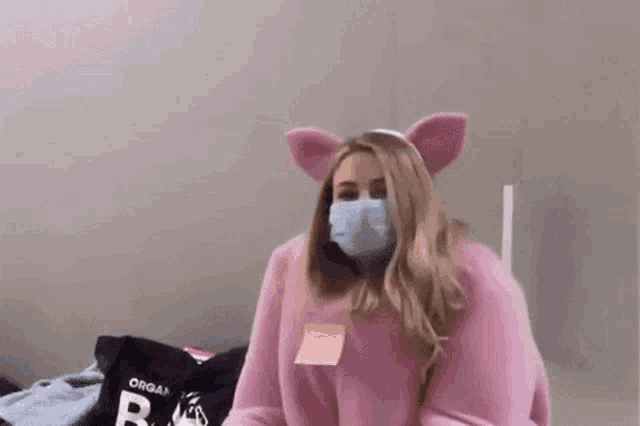 a woman in a pink pig costume is wearing a mask and ears .