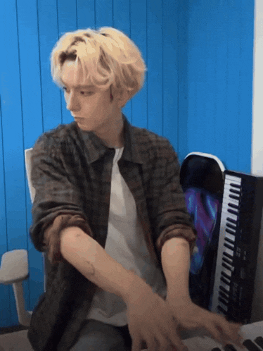 a man playing a keyboard with a blue wall in the background
