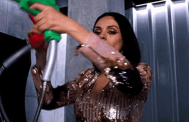 a woman in a sequined dress is pumping gas into a hose