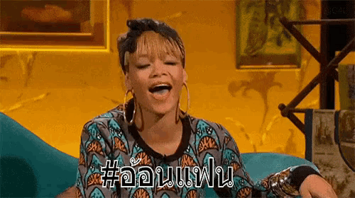 a woman is sitting on a blue couch with her mouth open and laughing .
