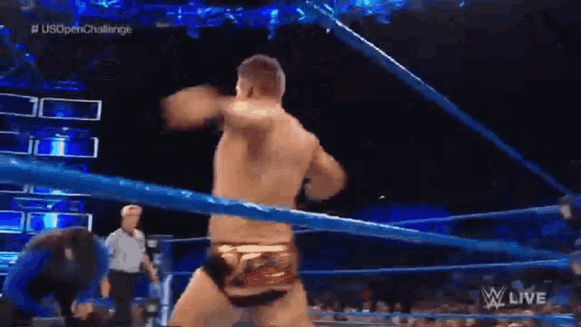 a wrestler is standing in a wrestling ring with a referee watching .