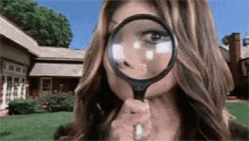 a woman is looking through a magnifying glass at a bug on her face .