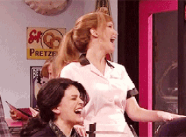 two women are laughing in front of a pretzel sign