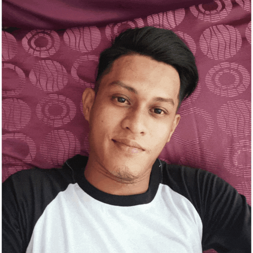 a young man laying on a bed with a purple blanket