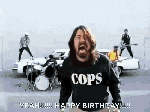 a man wearing a cops shirt is singing in front of a band .