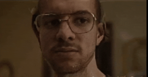 a man with glasses and a beard is looking at the camera in a close up .