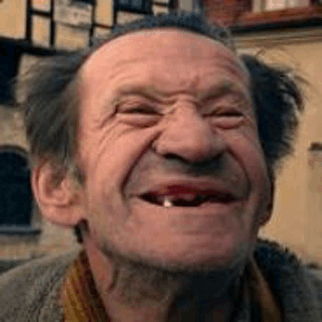 an elderly man with a missing tooth is smiling .