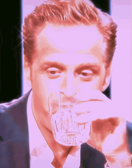 a man in a suit drinking from a glass