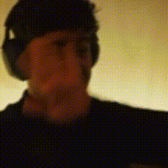 a man wearing headphones and a hat is standing in front of a yellow wall .