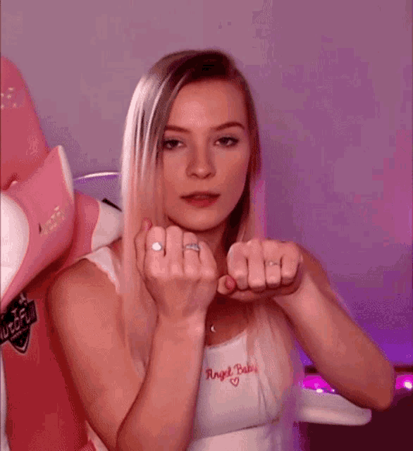 a woman wearing a white tank top with angel baby written on it