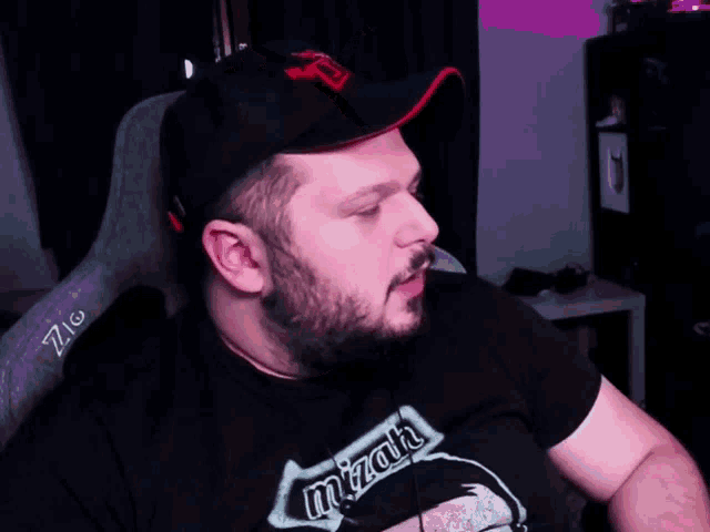 a man with a beard wears a black shirt that says mizah