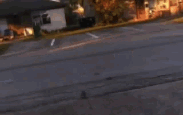 a black car is driving down a street in front of a house