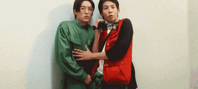 a man in a red vest is taking a picture of another man with a camera