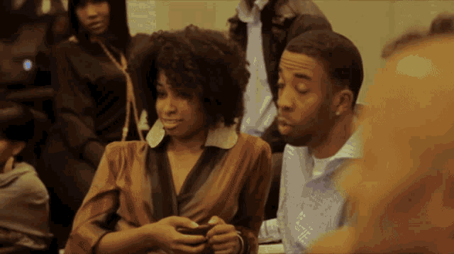 a man and a woman sit in a crowd looking at something