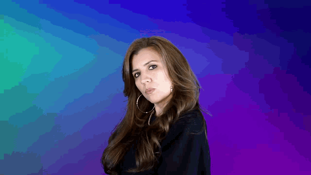 a woman with long hair and hoop earrings looks at the camera