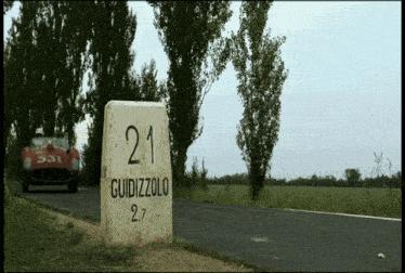 a car is driving down a road next to a stone that says 21 guidizzolo 2.7