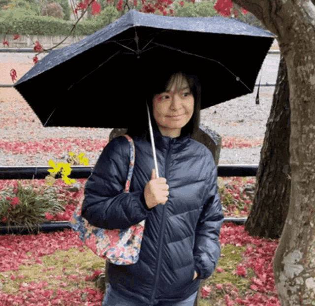 a woman in a blue jacket holding an umbrella in the rain