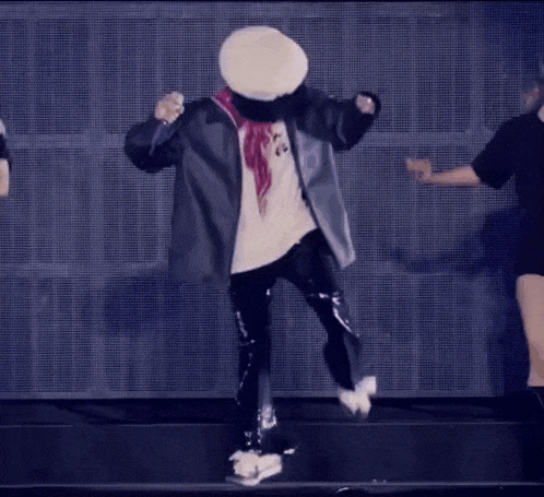 a man wearing a hat and scarf is dancing on stage