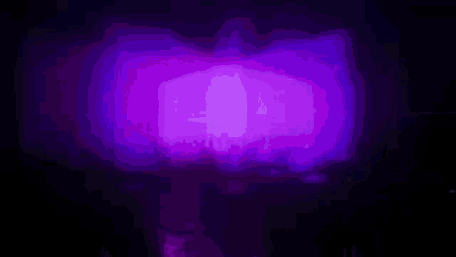 a purple light is shining on a black surface