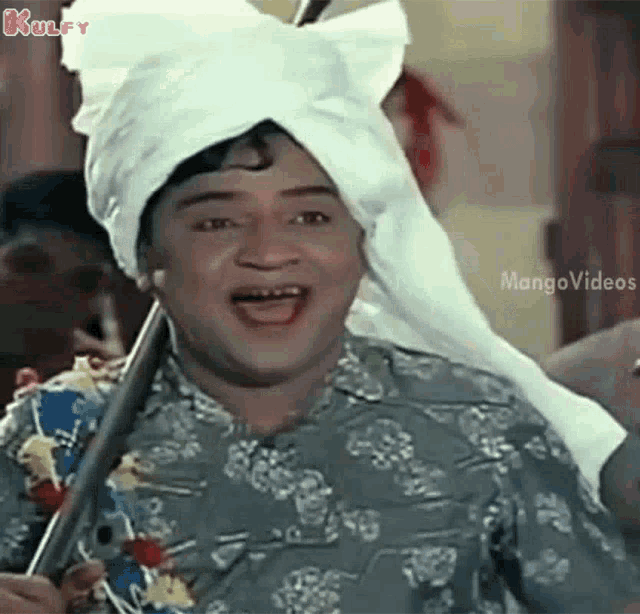 a man wearing a turban and holding a stick is laughing .