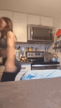 a woman in a bra is dancing in a kitchen