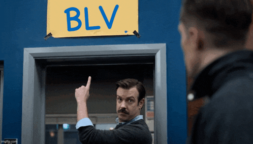 a man with a mustache points to a sign that says blv