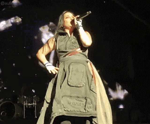 a woman is singing into a microphone on a stage