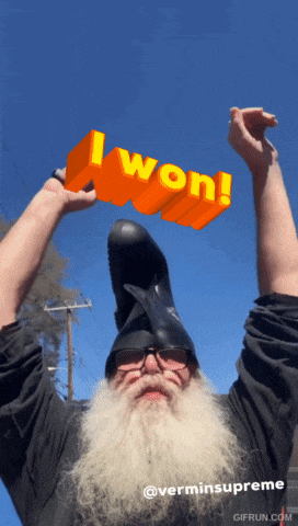a man with a beard is wearing a helmet and holding up an orange sign that says i won