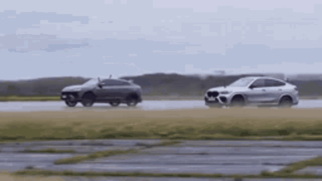 two cars are driving down a wet road on a rainy day .
