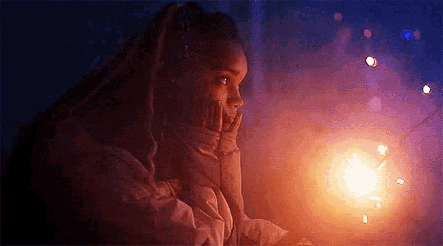 a woman is holding a sparkler in her hand and looking at it .