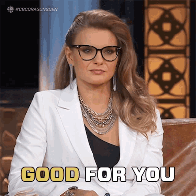 a woman wearing glasses and a white jacket is sitting on a couch and says good for you