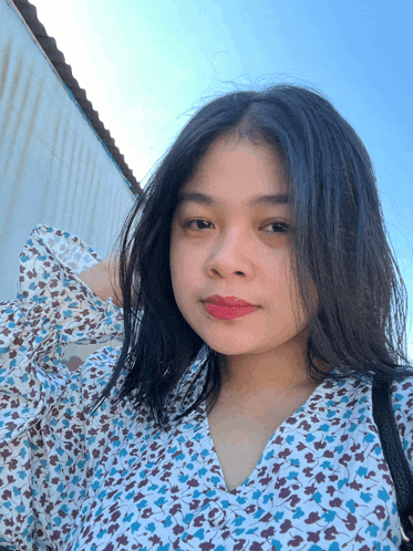 a woman wearing a blue and white floral shirt