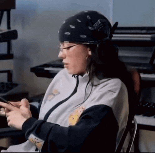 a woman wearing a bandana and glasses is looking at her phone