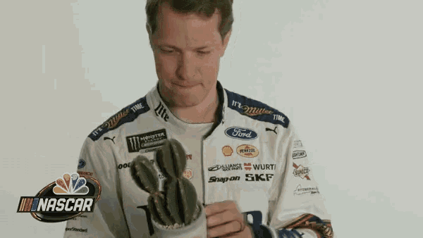 a man in a nascar shirt is holding a cactus in his hand
