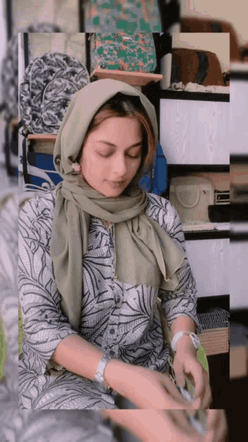a woman wearing a hijab and a watch looks down at something