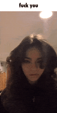 a girl with long hair is standing in front of a light with the words fuck you above her