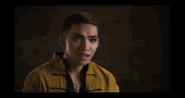 a woman in a yellow jacket is making a gesture