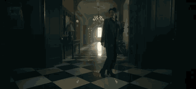 a woman walking down a hallway with checkered floors