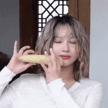 a woman is holding a corn on the cob in front of her mouth .
