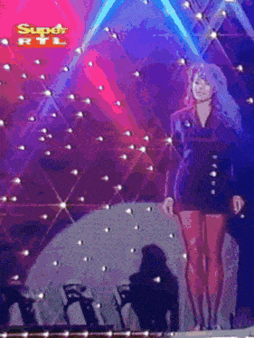 a woman stands on a stage with a super rtl logo in the background