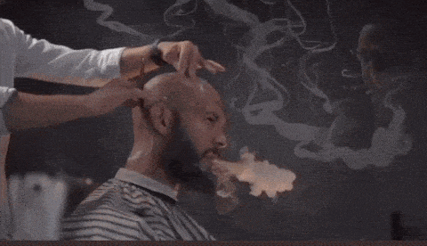 a man with a beard is getting a haircut with smoke coming out of his hair