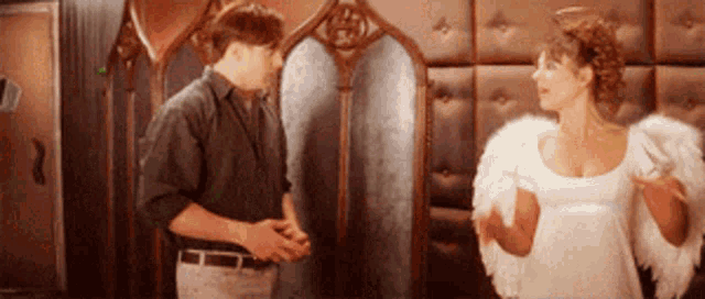 a man and a woman are standing next to each other and the woman is wearing wings