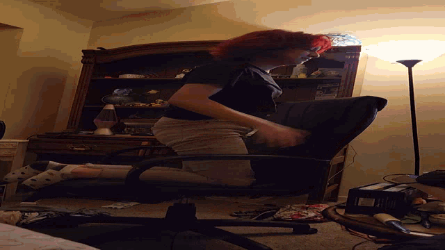 a person with red hair is sitting in a chair with a box on the floor