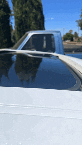 a white truck with a sunroof is parked on the side of a road