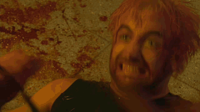 a man with blood on his face is laying on the floor with blood coming out of his mouth .