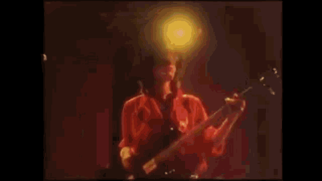 a man without a shirt is playing a guitar on a stage .
