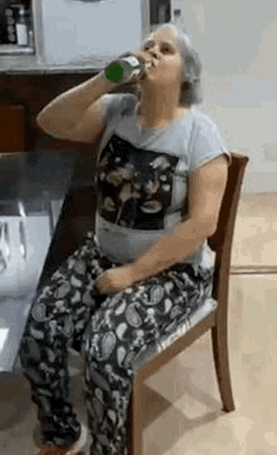 a woman is sitting in a chair drinking from a bottle of soda .