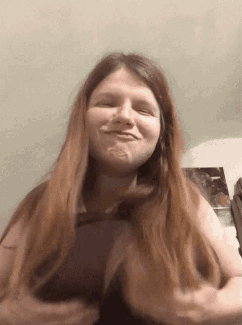 a woman with long red hair is smiling and making a funny face
