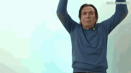 a man in a blue sweater is holding his arms in the air .
