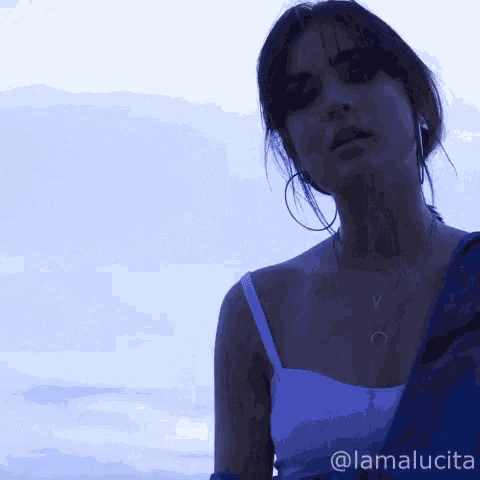 a woman in a white top is standing in front of a blue sky with the name lamalucia on the bottom right